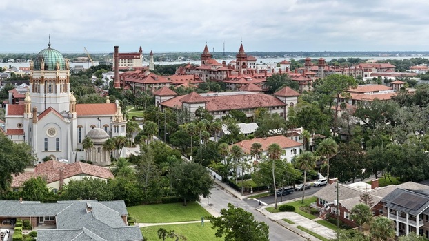 Aerial view of Memorial Presbyterian Church with its distinctive dome surrounded by historic red roofed buildings lush trees and urban streets St. Augustine Florida United States.