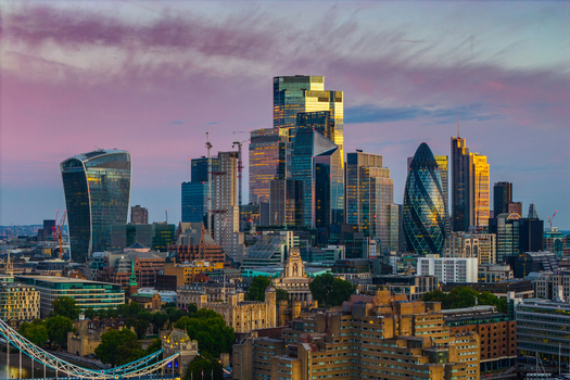 Aerial view of City of London skyline featuring iconic skyscrapers like The Gherkin under a vibrant sunset sky London England United Kingdom.