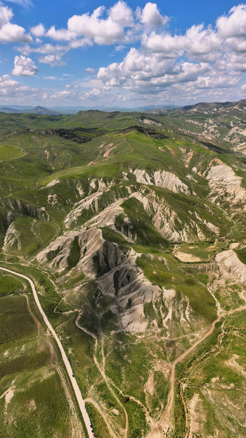 Aerial view of a landscape with rugged terrain under a blue sky dotted with puffy white clouds creating a serene yet dramatic vista Centuripe Sicilia Italy. Aerial view of a landscape with rugged terrain under a blue sky dotted with puffy white clouds creating a serene yet dramatic vista Centuripe Sicilia Italy.