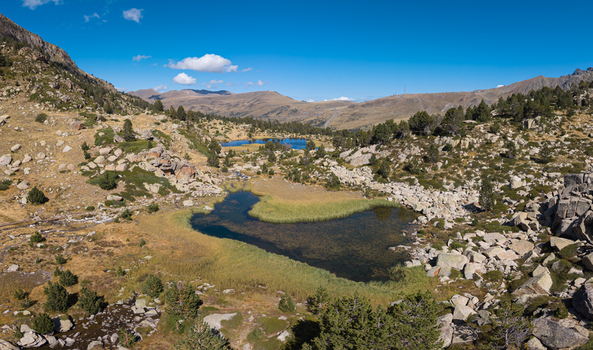 Aerial view of Llac de pessons surrounded by rocky alpine terrain and sparse vegetation in the mountains of Grau Roig Encamp Andorra. Aerial view of Llac de pessons surrounded by rocky alpine terrain and sparse vegetation in the mountains of Grau Roig Encamp Andorra.