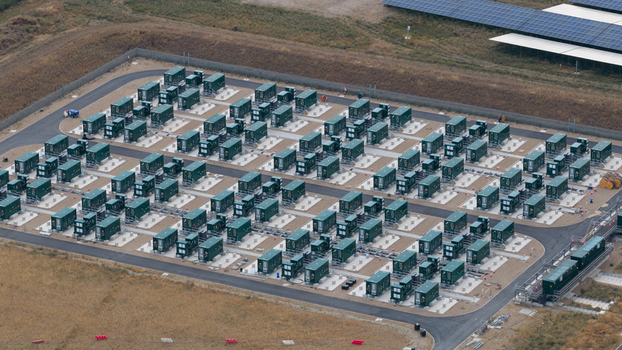 Aerial view of a large scale battery energy storage system with rows of green containers on concrete pads surrounded by gravel paths in London England United Kingdom.