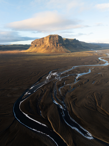 Aerial view of Lomagnupur mountain rising above the vast braided river system and dark volcanic sand plains in Skaftarhreppur Iceland.