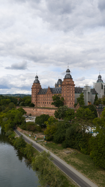 Aerial view of Schloss Johannisburg a historic Renaissance castle with red sandstone walls and towers situated along the Main river in Aschaffenburg Bayern Germany.