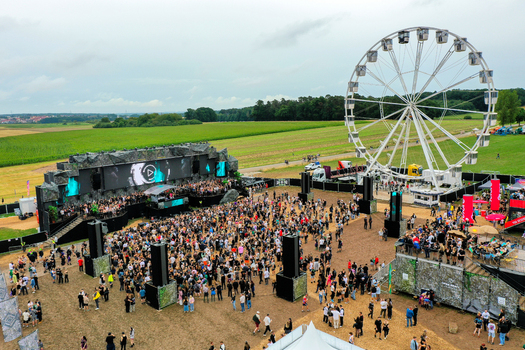 Herzogenaurach Germany 26 July 2025 Aerial view of the Open Beatz Festival featuring a large main stage a white Ferris wheel and a crowd of people gathered in an open field.