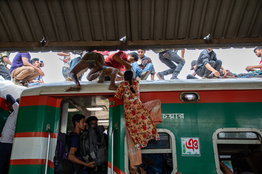 Dhaka Bangladesh 14 June 2018 View of people and a woman climbing onto the roof of a crowded train at Airport Railway Station during the Eid al Fitr holiday rush. Dhaka Bangladesh 14 June 2018 View of people and a woman climbing onto the roof of a crowded train at Airport Railway Station during the Eid al Fitr holiday rush.
