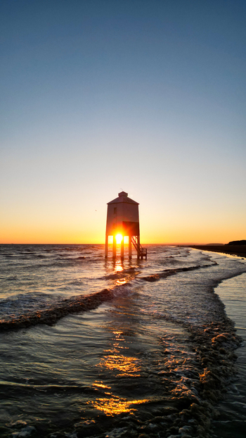 Aerial view of the historic Burnham on Sea Low Lighthouse standing in the tide at sunset with golden light reflecting on the wet sand and sea Burnham on Sea England United Kingdom. Aerial view of the historic Burnham on Sea Low Lighthouse standing in the tide at sunset with golden light reflecting on the wet sand and sea Burnham on Sea England United Kingdom.