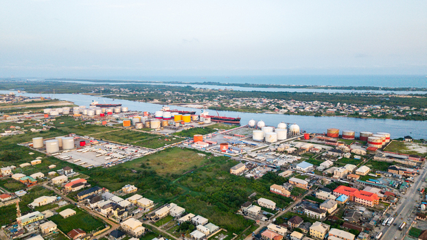 Aerial view of the industrial port area in Satellite Town featuring large storage tanks cargo ships docked along the river and surrounding residential neighborhoods in Lagos Lagos Nigeria.