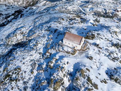 Aerial view of a solitary structure nestled amidst a snow dusted rocky landscape with the tranquil lake shimmering in the distance Lagoa Comprida São Romão Serra da Estrella Portugal. Aerial view of a solitary structure nestled amidst a snow dusted rocky landscape with the tranquil lake shimmering in the distance Lagoa Comprida São Romão Serra da Estrella Portugal.