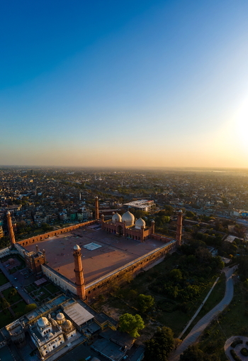 Aerial view of Badshahi Mosque with its iconic domes and minarets surrounded by the historic city landscape of Lahore at sunset in Lahore Punjab Pakistan. Aerial view of Badshahi Mosque with its iconic domes and minarets surrounded by the historic city landscape of Lahore at sunset in Lahore Punjab Pakistan.