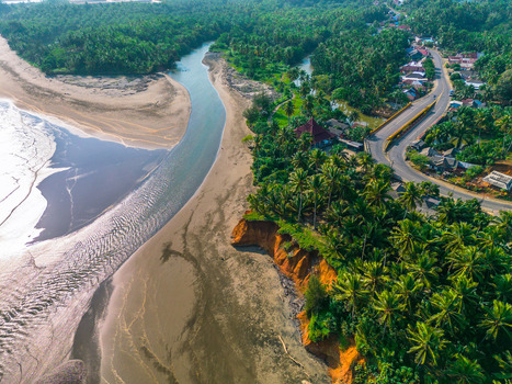 Aerial view of a river flowing into the sea surrounded by lush palm trees a sandy beach and a coastal road with a bridge in Bali Bali Indonesia. Aerial view of a river flowing into the sea surrounded by lush palm trees a sandy beach and a coastal road with a bridge in Bali Bali Indonesia.