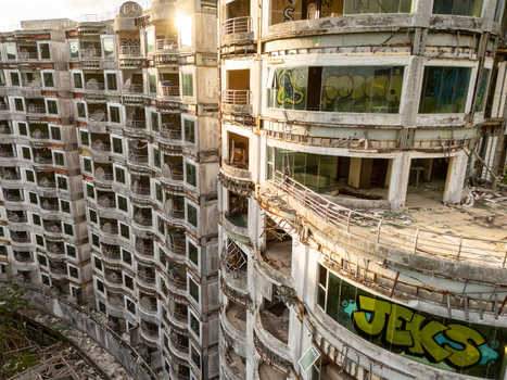 Aerial view of the abandoned Sonesta One Resort featuring graffiti covered walls empty balconies and concrete structure under golden sunlight in Jaco Provincia de Puntarenas Costa Rica. Aerial view of the abandoned Sonesta One Resort featuring graffiti covered walls empty balconies and concrete structure under golden sunlight in Jaco Provincia de Puntarenas Costa Rica.