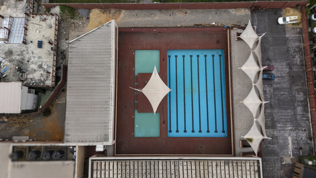 Aerial view of Lagos Island swimming pool complex featuring a large rectangular pool and a smaller pool with white shade sails on a red deck in Lagos Lagos Nigeria. Aerial view of Lagos Island swimming pool complex featuring a large rectangular pool and a smaller pool with white shade sails on a red deck in Lagos Lagos Nigeria.