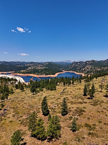 Aerial view of Walker Ranch and the surrounding reservoir with pine forests and mountain peaks under a clear blue sky in Boulder Colorado United States.