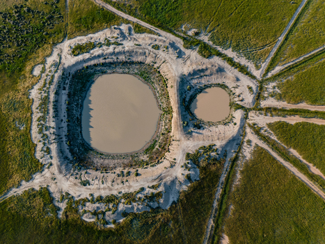Aerial view of two circular ponds surrounded by arid earth and green fields in the flat landscape of Hay New South Wales Australia.