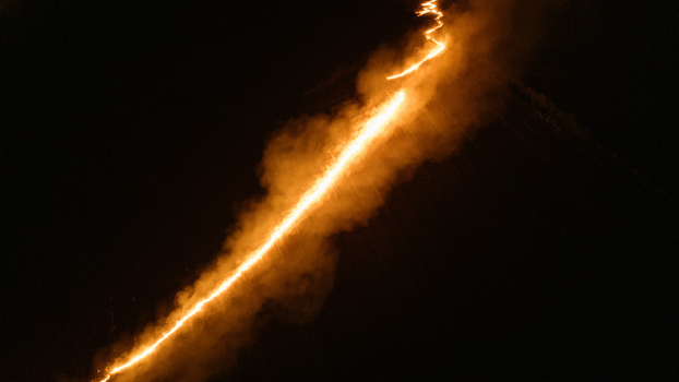 Aerial view of a bright glowing linear light trail cutting through the darkness of the night landscape in Sremska Mitrovica Vojvodina Serbia.