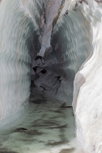 View of the icy crevasse of Baltoro Glacier with sculpted white ice walls and a stream of meltwater flowing through the center in Baltoro Gilgit Baltistan Pakistan.