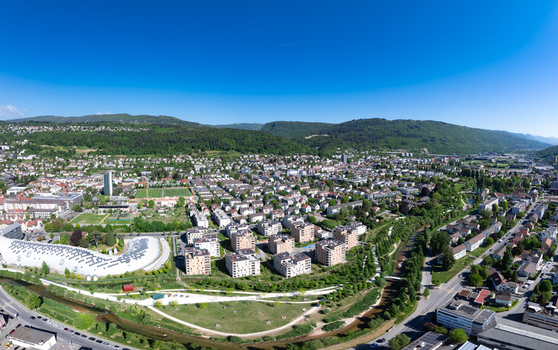 Aerial view of modern residential buildings and the Swatch Omega headquarters near the Suze river with lush green hills in Biel Bienne Canton of Bern Switzerland.