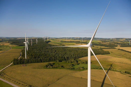 Aerial view of white wind turbines contrast against the dark green forest and gold fields under a clear blue sky Salles Curan Occitanie France. Aerial view of white wind turbines contrast against the dark green forest and gold fields under a clear blue sky Salles Curan Occitanie France.