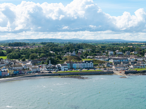 Aerial view of Donaghadee Harbour with its colorful waterfront buildings and historic lighthouse set against the green hills of the coast in Donaghadee Northern Ireland United Kingdom. Aerial view of Donaghadee Harbour with its colorful waterfront buildings and historic lighthouse set against the green hills of the coast in Donaghadee Northern Ireland United Kingdom.