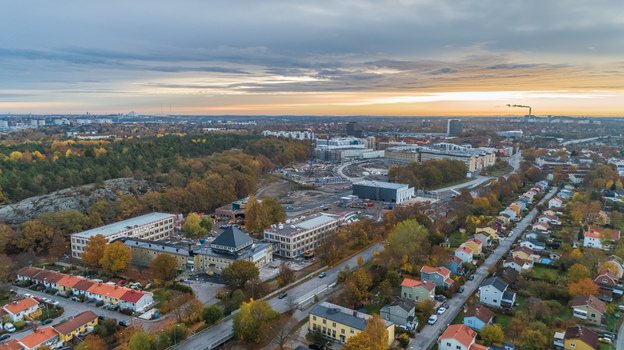 Aerial view of a suburban area featuring residential houses a construction site with modern buildings and surrounding autumn forests under a sunset sky in Sweden. Aerial view of a suburban area featuring residential houses a construction site with modern buildings and surrounding autumn forests under a sunset sky in Sweden.