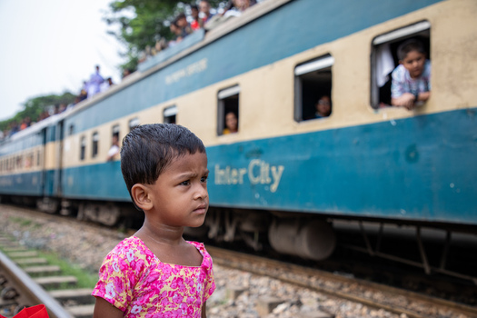Dhaka Bangladesh 14 June 2018 View of a young girl standing by the tracks as a crowded Inter City train arrives at the Airport Railway Station. Dhaka Bangladesh 14 June 2018 View of a young girl standing by the tracks as a crowded Inter City train arrives at the Airport Railway Station.