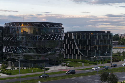 Aerial view of modern glass office buildings with curved facades and reflective surfaces surrounded by green lawns and a road with traffic in Krakow Lesser Poland Voivode Poland.