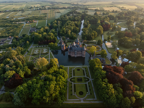 Aerial view of De Haar Castle surrounded by a moat formal gardens and lush green forests under soft evening light Utrecht Utrecht Netherlands. Aerial view of De Haar Castle surrounded by a moat formal gardens and lush green forests under soft evening light Utrecht Utrecht Netherlands.