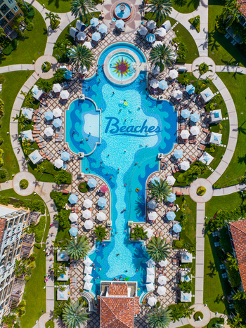 Aerial view of the swimming pool complex at Beaches Resort featuring turquoise water white umbrellas lush landscaping and palm trees in Grace Bay Caicos Islands Turks and Caicos Islands. Aerial view of the swimming pool complex at Beaches Resort featuring turquoise water white umbrellas lush landscaping and palm trees in Grace Bay Caicos Islands Turks and Caicos Islands.
