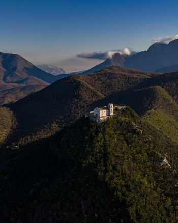 Aerial view of Santuario del Santissimo Salvatore on a lush green hilltop surrounded by the Apennine Mountains in Montella Campania Italy. Aerial view of Santuario del Santissimo Salvatore on a lush green hilltop surrounded by the Apennine Mountains in Montella Campania Italy.