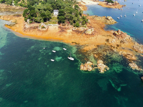 Aerial view of Brehat island featuring rocky coastline turquoise waters and anchored sailboats Ile de Brehat Brittany France.