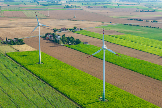 Aerial view of wind turbines in a rural landscape with green fields and agricultural land in Poland.