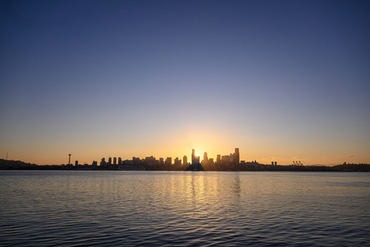 View of the Seattle skyline at sunset with the sun behind skyscrapers reflecting on the calm waters of Elliott Bay seen from Don Armeni Boat Ramp in Seattle Washington United States. View of the Seattle skyline at sunset with the sun behind skyscrapers reflecting on the calm waters of Elliott Bay seen from Don Armeni Boat Ramp in Seattle Washington United States.