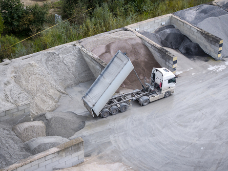 Aerial view of a dump truck unloading gravel at the Holcim concrete plant surrounded by storage bays and industrial infrastructure in Krakow Lesser Poland Voivode Poland.