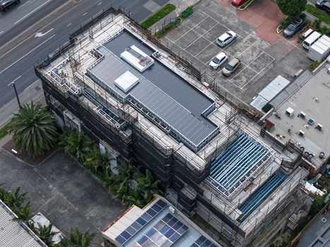 Melbourne VIC Australia 25 September 2026 Aerial view of a building under construction featuring scaffolding metal roof framing and a surrounding parking lot.