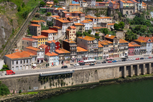 Aerial view of vibrant buildings with terracotta roofs cascade down to the Douro River s edge creating a rich tapestry of color and texture Porto Porto District Portugal. Aerial view of vibrant buildings with terracotta roofs cascade down to the Douro River s edge creating a rich tapestry of color and texture Porto Porto District Portugal.
