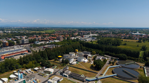 Aerial view of a wastewater treatment plant with circular sedimentation tanks industrial infrastructure and surrounding green fields near the urban landscape of Milan Lombardy Italy. Aerial view of a wastewater treatment plant with circular sedimentation tanks industrial infrastructure and surrounding green fields near the urban landscape of Milan Lombardy Italy.