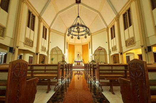 View of the interior of Saint Joseph Catholic Church featuring wooden pews a central aisle and a large chandelier in Kecamatan Ambarawa Jawa Tengah Indonesia.