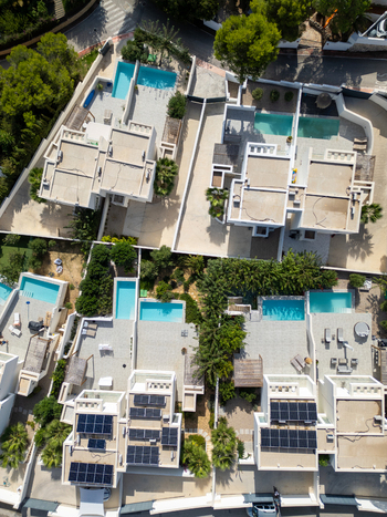 Aerial view of modern residential villas featuring private swimming pools rooftop solar panels and lush landscaping in Moraira Valencian Community Spain.