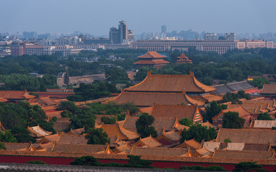 View of the Forbidden City with its iconic orange tiled roofs and traditional Chinese architecture set against the modern skyline of Beijing Beijing China. View of the Forbidden City with its iconic orange tiled roofs and traditional Chinese architecture set against the modern skyline of Beijing Beijing China.