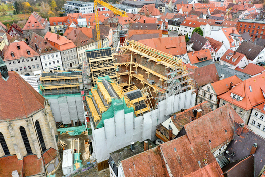Aerial view of the Rathaus Forchheim under renovation with extensive scaffolding and a yellow crane surrounded by historic red roofed houses in Forchheim Bayern Germany. Aerial view of the Rathaus Forchheim under renovation with extensive scaffolding and a yellow crane surrounded by historic red roofed houses in Forchheim Bayern Germany.