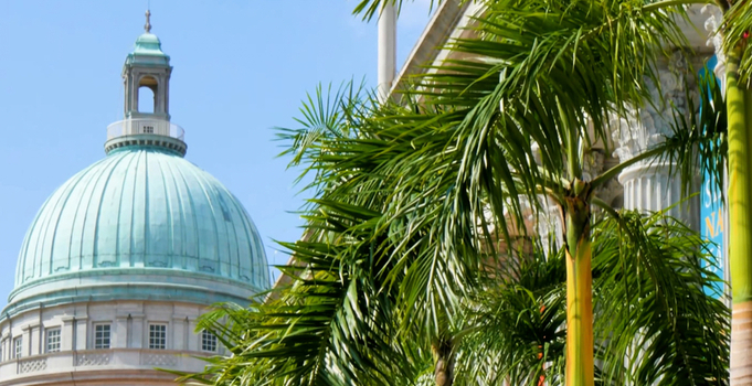 View of the Former Supreme Court building with its iconic copper dome framed by lush palm trees under a clear blue sky in Singapore Singapore. View of the Former Supreme Court building with its iconic copper dome framed by lush palm trees under a clear blue sky in Singapore Singapore.