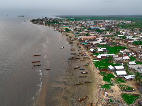 Aerial view of Bonny Island with wooden boats moored along the shoreline residential buildings and the Atlantic Ocean in Bonny Town Rivers Nigeria. Aerial view of Bonny Island with wooden boats moored along the shoreline residential buildings and the Atlantic Ocean in Bonny Town Rivers Nigeria.
