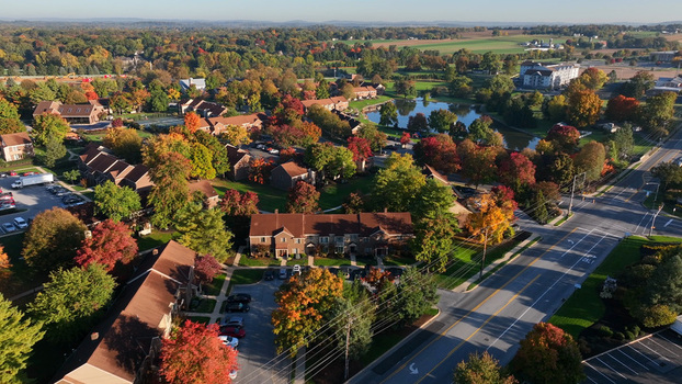 Aerial view of a residential neighborhood with vibrant autumn foliage a small pond and local roads in East Lampeter Township Pennsylvania United States.