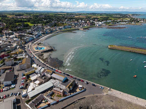 Aerial view of Donaghadee Harbour with its coastal town buildings sandy beach and calm sea in Donaghadee Northern Ireland United Kingdom. Aerial view of Donaghadee Harbour with its coastal town buildings sandy beach and calm sea in Donaghadee Northern Ireland United Kingdom.