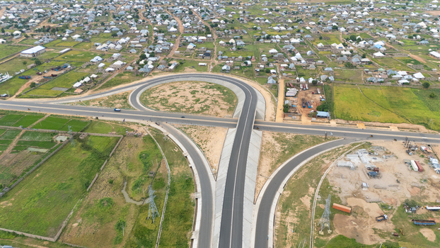 Aerial view of a modern highway interchange with smooth asphalt roads and concrete overpasses surrounded by residential areas and green fields in Yola Adamawa Nigeria. Aerial view of a modern highway interchange with smooth asphalt roads and concrete overpasses surrounded by residential areas and green fields in Yola Adamawa Nigeria.