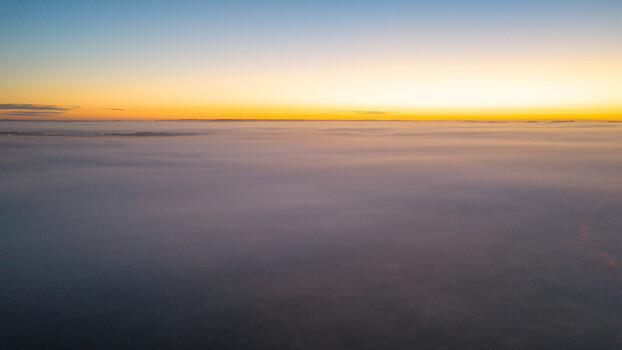 Aerial view of a vast sea of thick fog covering the landscape during a golden sunrise in Salisbury England United Kingdom. Aerial view of a vast sea of thick fog covering the landscape during a golden sunrise in Salisbury England United Kingdom.