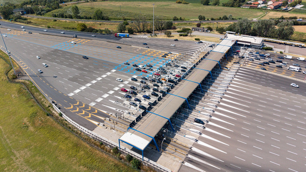 Aerial view of the Autostrada A1 Melegnano toll plaza with vehicles passing through the toll gates highway infrastructure and surrounding landscape in Melegnano Lombardy Italy.
