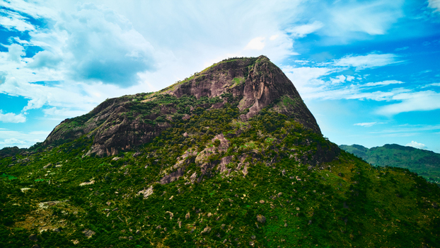 Aerial view of a majestic mountain its rocky peak piercing the sky amidst lush green slopes contrasting with the azure horizon Colombo Sri Lanka.