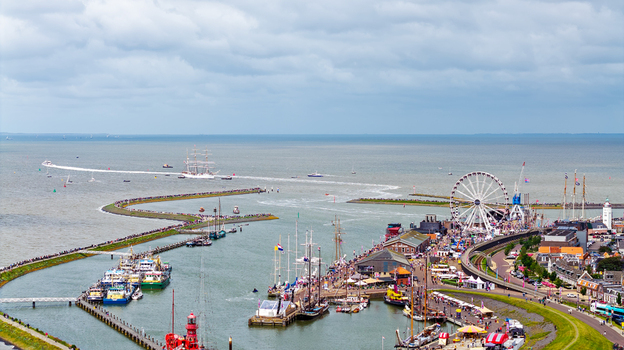 Aerial view of The Tall Ships Races Harlingen featuring historic sailing vessels a large Ferris wheel and crowds along the harbor in Harlingen Friesland Netherlands.