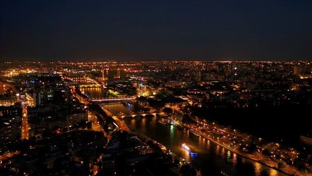 Aerial view of the illuminated Paris cityscape at night featuring the Seine river glowing bridges and dense urban lights stretching to the horizon in Paris Ile de France France. Aerial view of the illuminated Paris cityscape at night featuring the Seine river glowing bridges and dense urban lights stretching to the horizon in Paris Ile de France France.